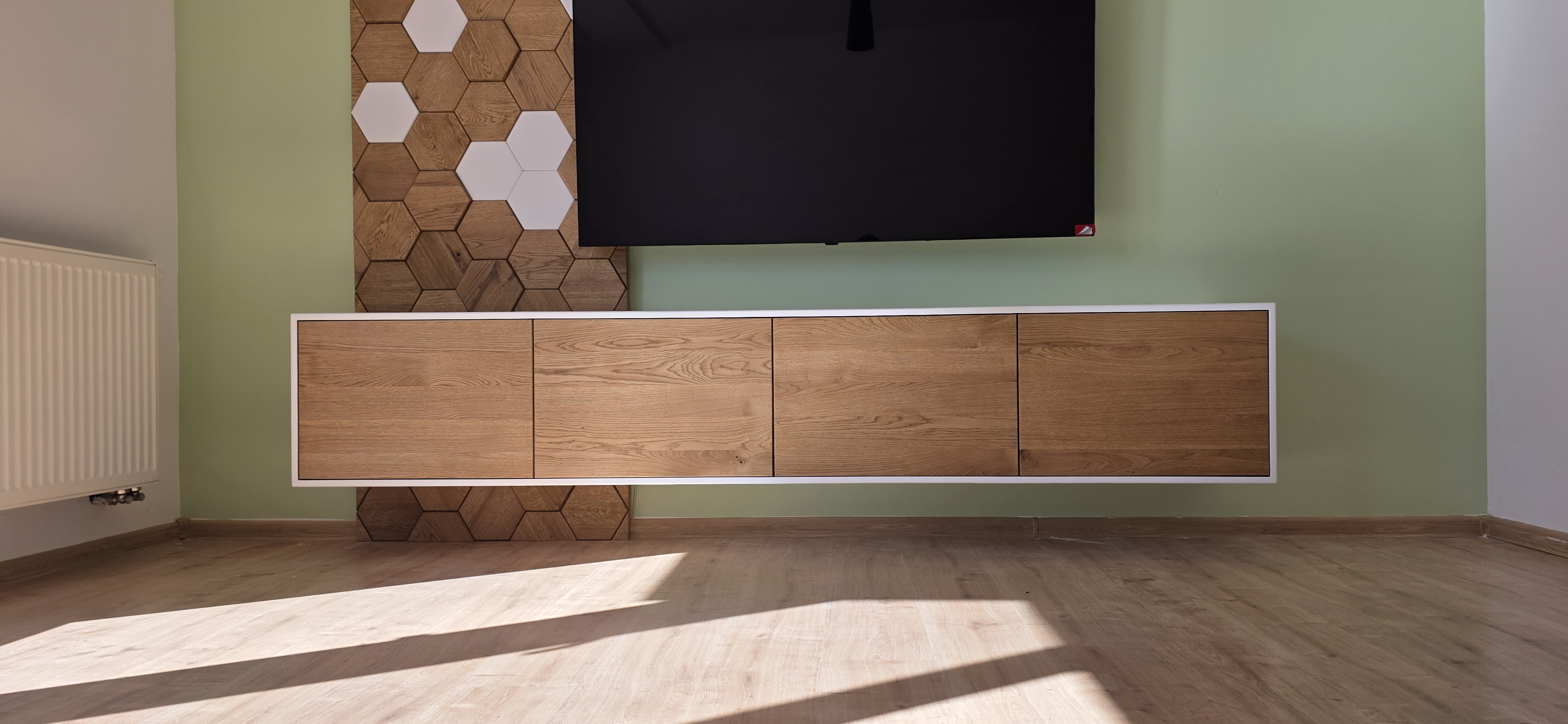 Závesná TV skrinka s hexagonovým obkladom steny